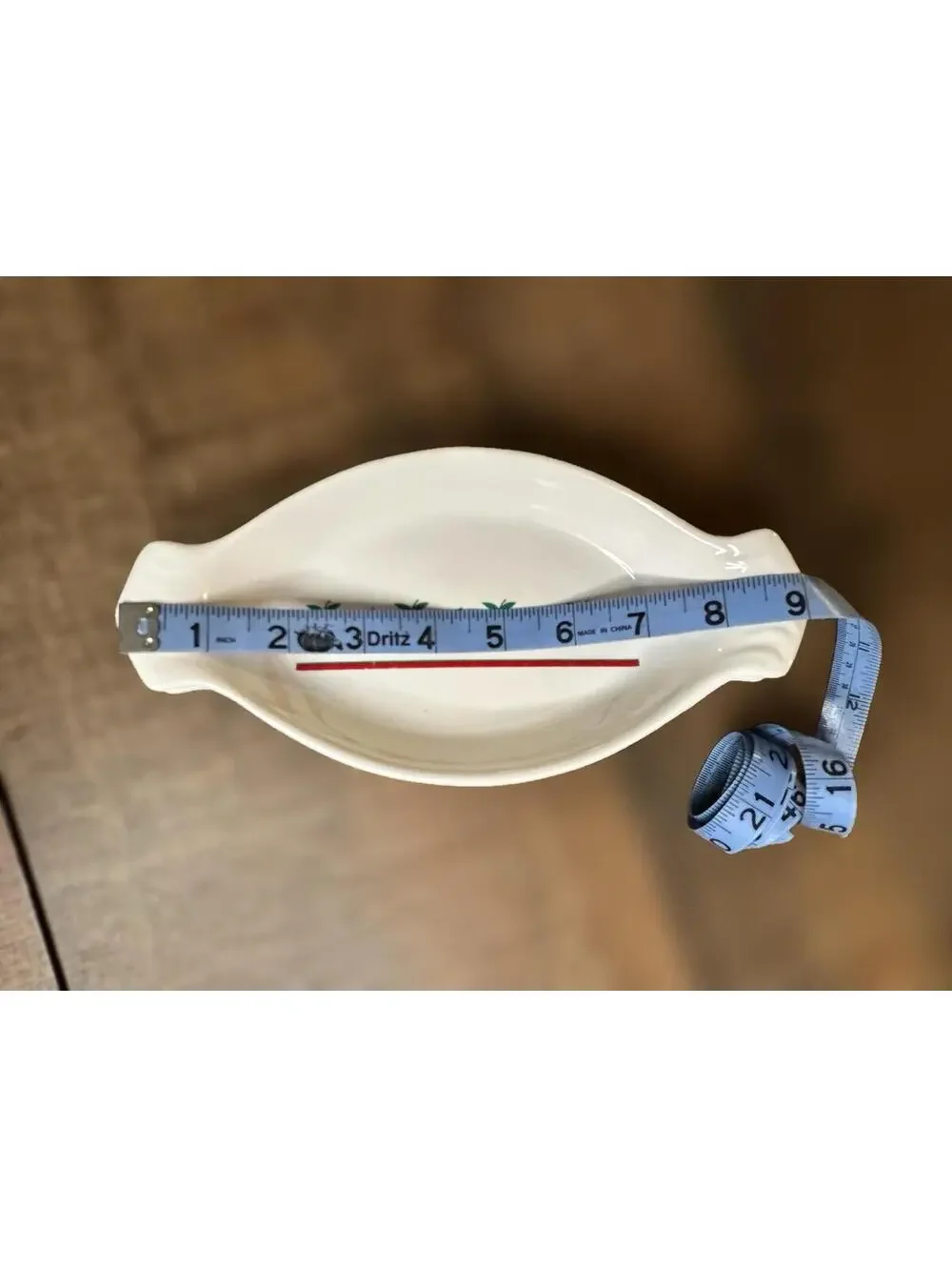 White ceramic oval au gratin dish with red apple and green leaf decoration.